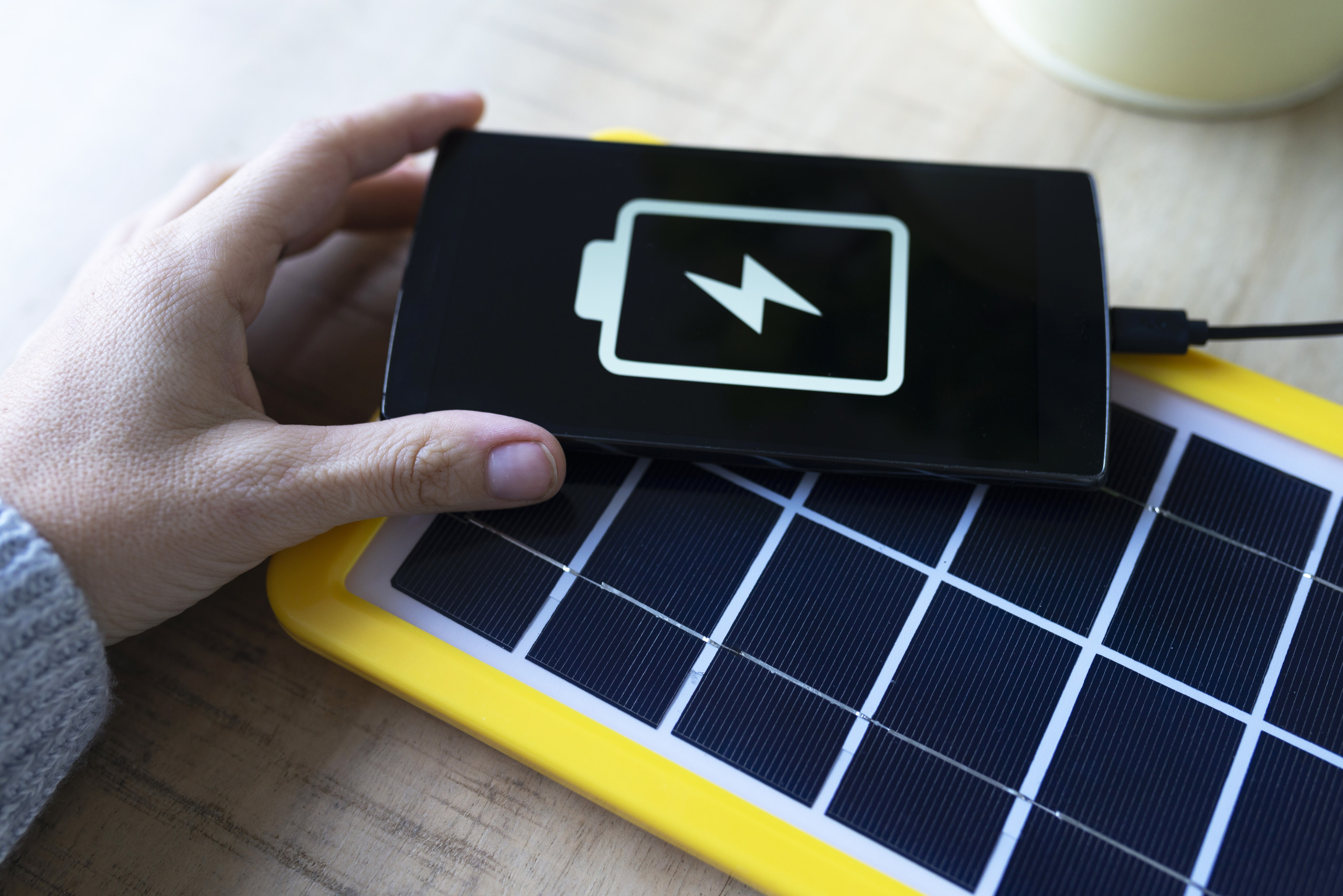 Renewable energy technology, solar panel charging a mobile phone battery Renewable energy technology, solar panel charging a mobile phone battery