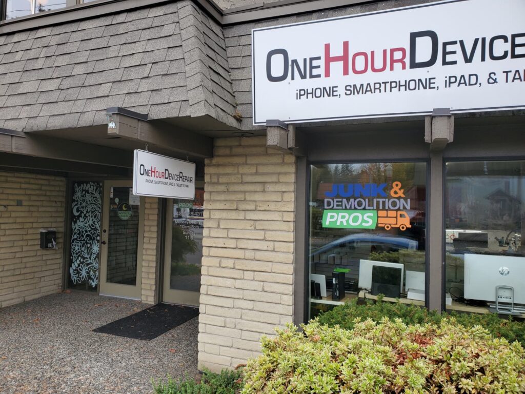 The One Hour Device Repair storefront in Issaquah, with the mascot holding a “We Fix Phones” sign